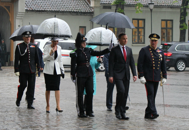 W strugach deszczu. Królewska para oraz prezydent Duda wraz małżonką zmierzają w kierunku Pomnika Niepodległości.
